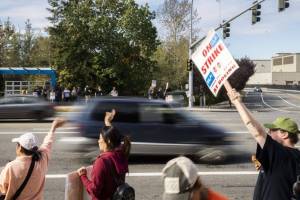 Cars drive past Boeing workers waving signs while picketing along Airport Road on Tuesday, Oct. 1, 2024 in Everett, Washington. (Olivia Vanni / The Herald)