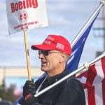 Bill Studerus, a Boeing Machinist for 39 years, holds a Boeing strike sign, an American flag and a campaign flag for former President Donald Trump while picketing at the Boeing plant on Thursday, Oct. 24, 2024, in Everett, Washington. (Michael Henneke / The Herald)