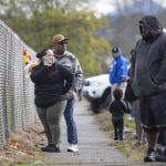 People gather along the fence surrounding Marysville Pilchuck High School after the school was placed on lockdown on Friday, Oct. 25, 2024 in Marysville, Washington. (Olivia Vanni / The Herald)