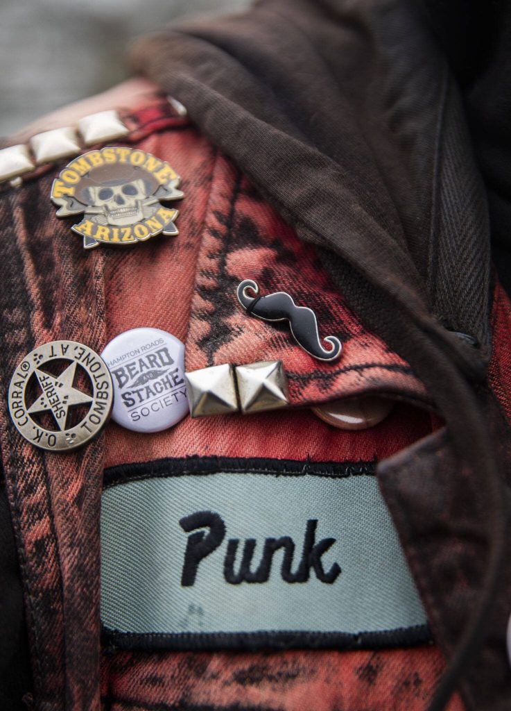 John Banks displays mustache and beard themed pins on his jean jacket during the Guinness World Record Beard Chain Attempt on Friday, Nov. 1, 2024 in Everett, Washington. (Olivia Vanni / The Herald)