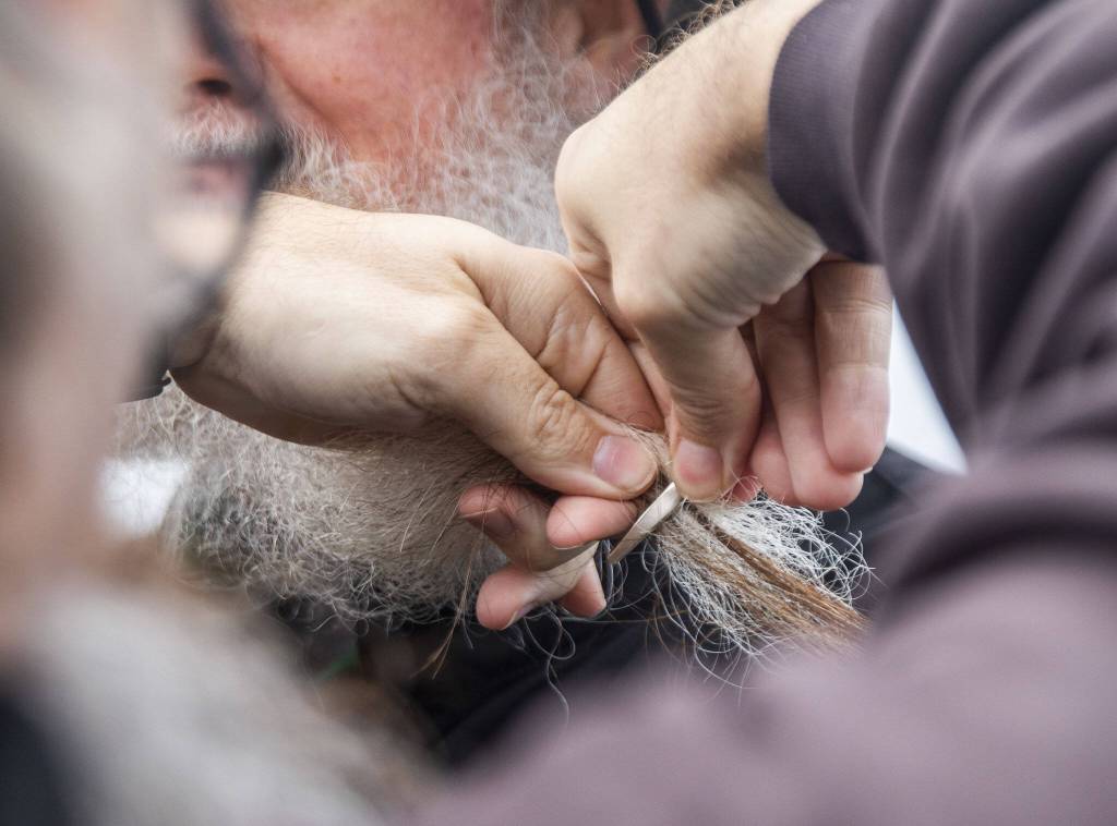 Particpants in the Guinness World Record Beard Chain Attempt have their beards clipped together on Friday, Nov. 1, 2024 in Everett, Washington. (Olivia Vanni / The Herald)