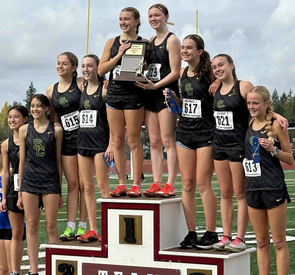 Members of the Shorecrest High School girls cross country team lift the 3A district trophy at the District 1/2 Cross Country Championships at Lakewood High School in Arlington, Wash., on Nov. 2, 2024. (Photo courtesy of Shane Peterson)
