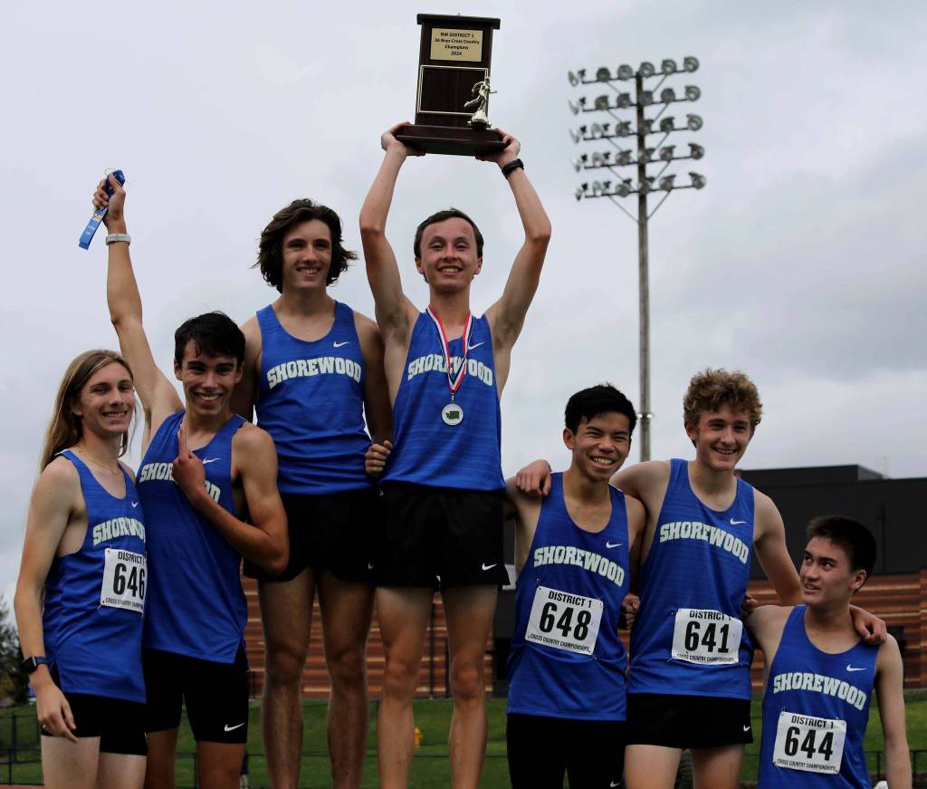 Members of the Shorewood High School boys cross country team lift the 3A district trophy at the District 1/2 Cross Country Championships at Lakewood High School in Arlington, Wash., on Nov. 2, 2024. Max Billett (center with trophy) bested teammate Otto Erhart (left of Billett) to win the individual medal. (Taras McCurdie / The Herald)