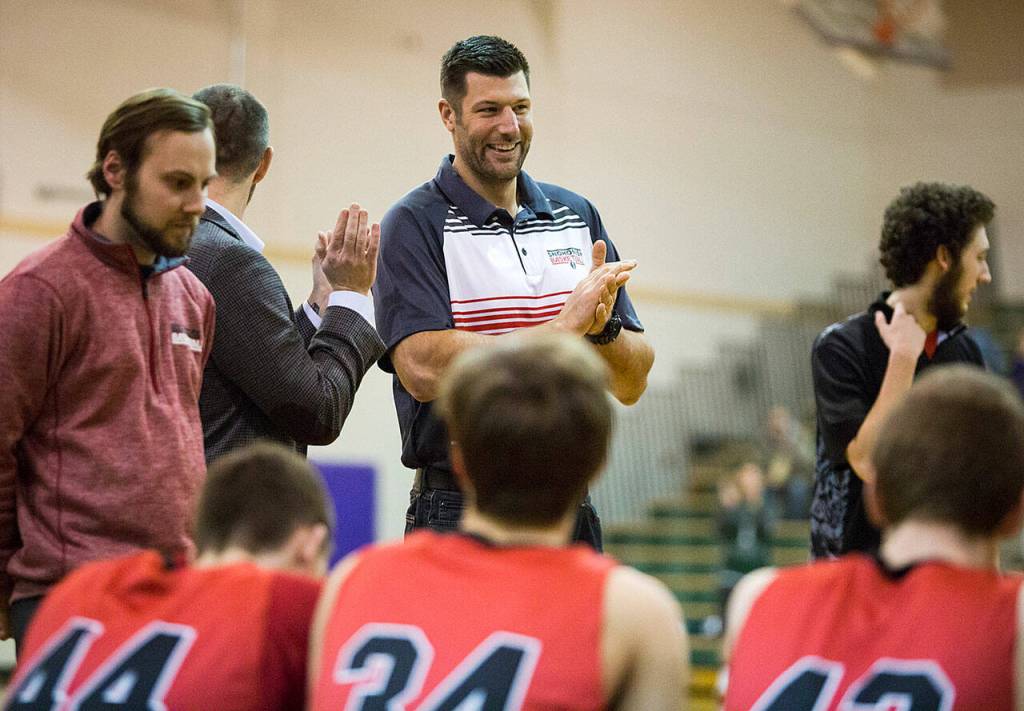 Snohomish varsity assistant and former NBA player John Brockman applauds after a group huddle before the game at Edmonds-Woodway High School in 2017. (Daniella Beccaria / Herald file)