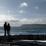 A couple stands on a large piece of driftwood in the wind at Mukilteo Lighthouse Park on Friday, Jan. 4, 2018 in Mukilteo, WA. There is a small craft advisory in effect until 10 pm Friday. (Olivia Vanni / The Herald)