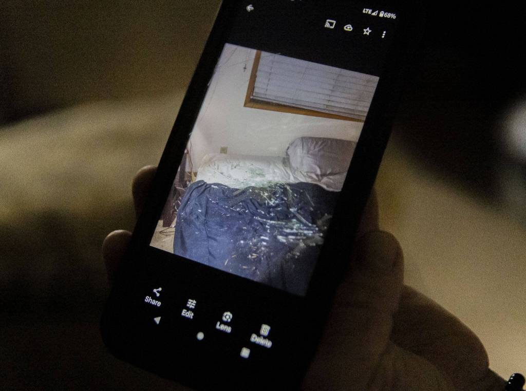 Hawes shows a photo of the glass that covered his bed after part of a tree shattered his window on Wednesday, Nov. 20, 2024 in Lake Stevens, Washington. (Olivia Vanni / The Herald)