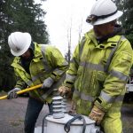 Drew Windsor, left, hits a transformer while Bryan Tugaw, right, holds it on Friday, Nov. 22, 2024, outside of Lake Stevens, Washington. The two are from Okanogan County. (Will Geschke / The Herald)