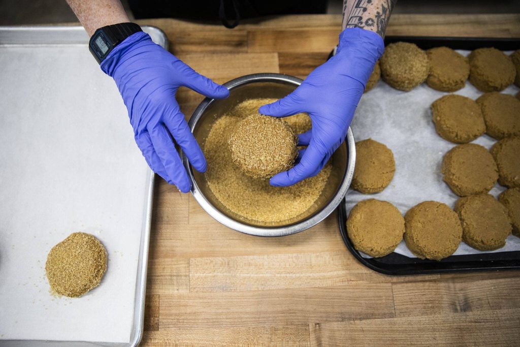 Katherine Hillman covers her ginger molasses cookie dough in sugar before placing them on a cookie sheet on Wednesday, Oct. 2, 2024 in Everett, Washington. (Olivia Vanni / The Herald)