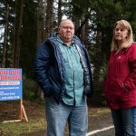35th Avenue neighborhood residents John Ray, left, and Shelia Davis, right, next to one of many signs scattered throughout the neighborhood look for community support on Friday, Dec. 20, 2024 in Marysville, Washington. (Olivia Vanni / The Herald)
