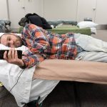 Justin Roeth lies on a bed on Monday, Dec. 2, 2024, at the Marysville Cold Weather Shelter in Marysville, Washington. (Will Geschke / The Herald)