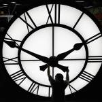 Electric Time technician Dan LaMoore adjusts a clock hand on a 1,000-pound, 12-foot diameter clock built for a resort in Vietnam, in March 2021, in Medfield, Mass. A bill before the Washington state Legislature could make standard time permanent in Washington, ending the twice-yearly switch between standard time and daylight saving time. (Elise Amendola / Associated Press file photo)