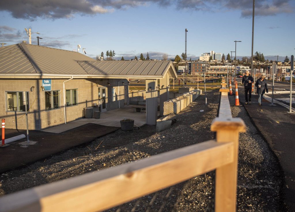 People walk past the public restroom at the Port of Everett that now sit lower than the renovated parking lot on Monday, Dec. 9, 2024 in Everett, Washington. (Olivia Vanni / The Herald)