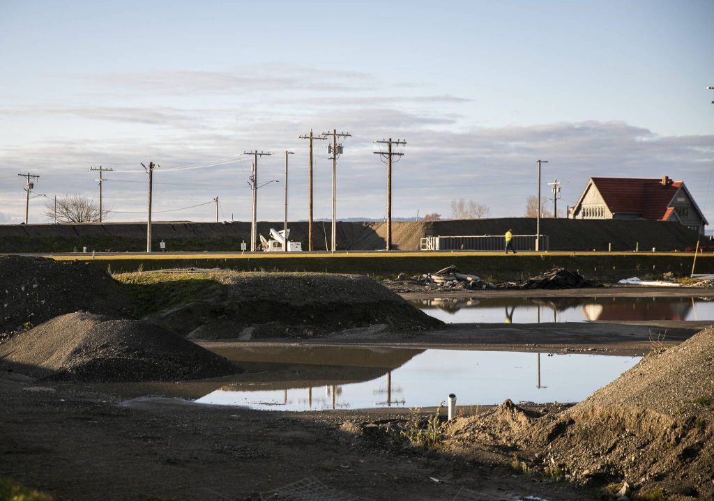 Piles of fill dirt are reflected in puddles at the Port of Everett on Monday, Dec. 9, 2024 in Everett, Washington. (Olivia Vanni / The Herald)