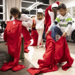 Elizabeth Gonzales, 8, left, and Lucas Rodriguez Hatch, 8, right, put on their oversized jumpsuits before the start of Toyota Mini Makers Garage on Monday, Dec. 9, 2024 in Marysville, Washington. (Olivia Vanni / The Herald)