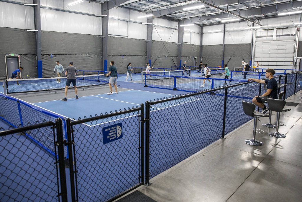 People play pickleball on multiple courts at the new Side Out Pickleball Centers on Wednesday, Dec. 18, 2024 in Everett, Washington. (Olivia Vanni / The Herald)