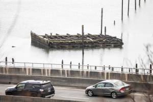 Cars drive along West Marine View Drive past a derelict barge visible off of the shoreline on Wednesday, Dec. 18, 2024 in Everett, Washington. (Olivia Vanni / The Herald)
