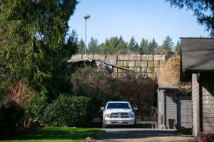A cement block wall holds back refuse at United Recycling and Containers behind a home on Tuesday, March 5, 2024, in Snohomish, Washington. Years ago, the homes on 109th Ave SE overlooked a 150-foot drop into an old gravel pit. (Ryan Berry / The Herald)