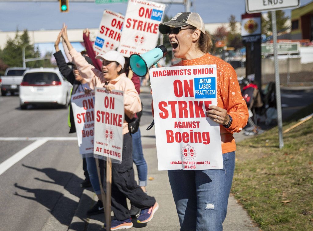 Jan James, a material processing specialist team lead who has been with Boeing for 22 years, uses a small megaphone to encourage drivers to honk in support of workers picketing along Airport Road on Tuesday, Oct. 1, 2024 in Everett, Washington. (Olivia Vanni / The Herald)