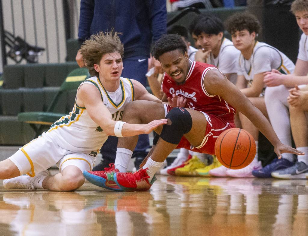 Cascades Noel Kisanga and Shorecrests Porter Swanson scramble for a loose ball during the game on Monday, Dec. 30, 2024 in Shoreline, Washington. (Olivia Vanni / The Herald)