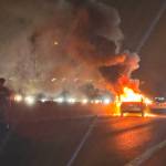 Two people stand on the highway as a car burns in the southbound lanes of Interstate 5 on Monday, Dec. 30 near Mountlake Terrace, Washington. (Eliza Aronson / The Herald)