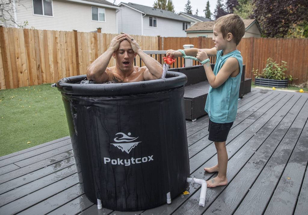 Jared Mead takes a breath after dunking in an ice bath in his back yard while his son Fallen, 5, reads off the water temperature on Tuesday, Oct. 15, 2024 in Everett, Washington. (Olivia Vanni / The Herald)