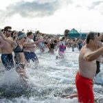 People sprint into the frigid waters of the Puget Sound to help ring in the new year during the 2023 Edmonds Polar Bear Plunge on Sunday, Jan. 1, 2023, at Brackett’s Landing in Edmonds, Washington. (Ryan Berry / The Herald)