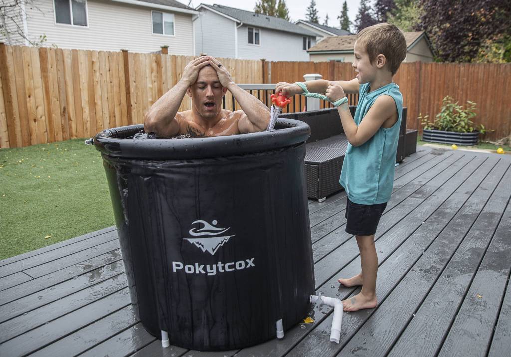 Photos By Olivia Vanni / The Herald
Jared Mead takes a breath after dunking in an ice bath in his back yard while his son Fallen, 5, reads off the water temperature on Oct. 15 in Everett.