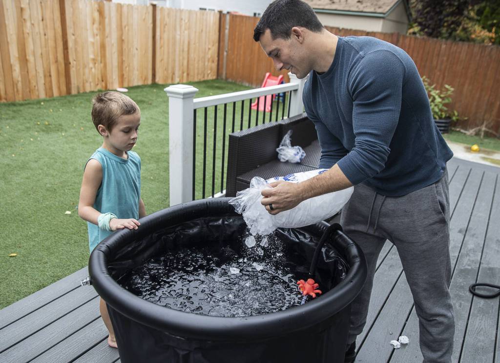 Jared Mead takes a breath after dunking in an ice bath in his back yard while his son Fallen, 5, reads off the water temperature on Tuesday, Oct. 15, 2024 in Everett, Washington. (Olivia Vanni / The Herald)