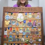 Robin Cain with 50 of her marathon medals hanging on a display board she made with her father on Thursday, Jan. 2, 2025 in Lake Stevens, Washington. (Olivia Vanni / The Herald)