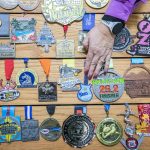 Robin Cain adjusts one of her marathon medals on Thursday, Jan. 2, 2025 in Lake Stevens, Washington. (Olivia Vanni / The Herald)
