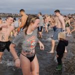 Kaley Rose runs out of the Puget Sound after taking the cold plunge on Wednesday, Jan. 1, in Edmonds, Washington. (Will Geschke / The Herald)
