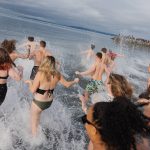 People rush into the cold water of the Edmonds shoreline on Wednesday, Jan. 1, in Edmonds, Washington. (Will Geschke / The Herald)