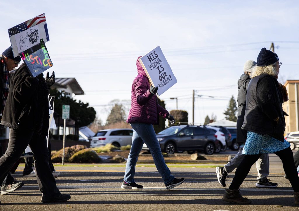 A person walking in an annual Martin Luther King Jr. Day march holds a sign that reads, His dream is our dream! on Monday, Jan. 20, 2025 in Everett, Washington. (Olivia Vanni / The Herald)