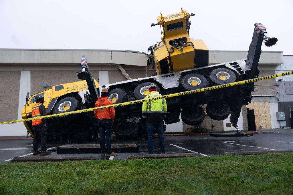 Construction workers look at a crane which crashed into a section of the Everett Mall on Thursday, Jan. 16, 2025 in Everett, Washington. (Will Geschke / The Herald)