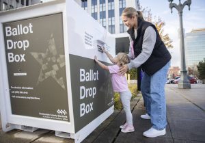 Carli Brockman lets her daughter Carli, 2, help push her ballot into the ballot drop box on the Snohomish County Campus on Tuesday, Nov. 5, 2024 in Everett, Washington. (Olivia Vanni / The Herald)