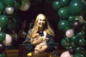 Kristi Kingma, carrying one of her children, walks through the balloon arch at an Athletic Hall of Fame ceremony at Jackson High School in Mill Creek on Jan. 17. (Aaron Coe / The Herald)