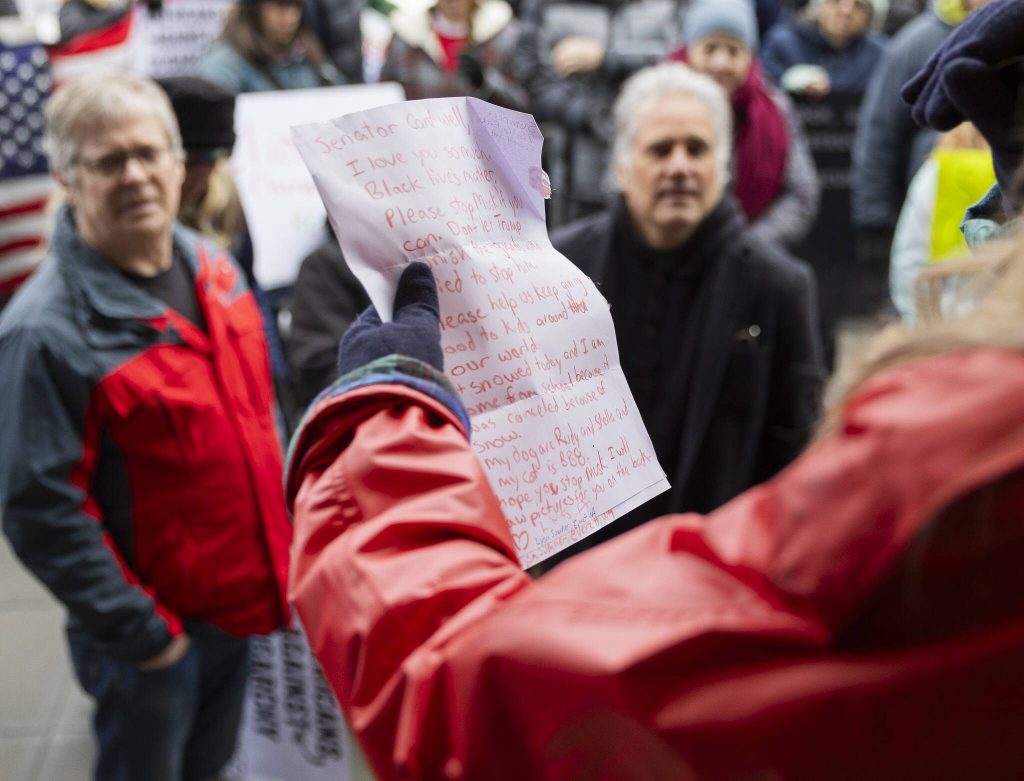 A letter written in orange crayon from a young Everett resident is read to a crowd gathered during a rally organized by Snohomish County Indivisible on Wednesday, Feb. 5, 2025 in Everett, Washington. (Olivia Vanni / The Herald)