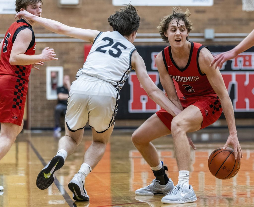 Snohomishs Bryson Wheat crosses the ball between his legs to keep it away from the outstretched arm of Mountlake Terraces Jordan Wilson during the 3A district loser-out playoff game on Thursday, Feb. 13, 2025 in Mountlake Terrace, Washington. (Olivia Vanni / The Herald)