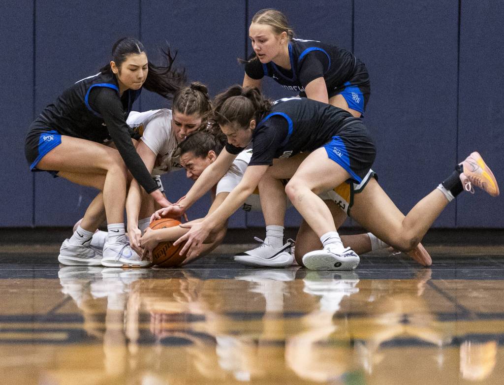 Shorewood and Shorecrest players scramble for a loose ball under the basket during the 3A district playoff game on Friday, Feb. 14, 2025 in Shoreline, Washington. (Olivia Vanni / The Herald)