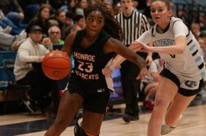 Monroe's Halle Keller drives past Meadowdale's Payton Fleishman during a Feb. 14, 2025 3A District 1 playoff game at Meadowdale High School. (Qasim Ali / The Herald)