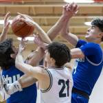 Edmonds-Woodways Luke Boland and Shorewoods Jaden Marlow and Max Nguyen get tangled midair while reaching for a rebound during the 3A district semifinal game on Wednesday, Feb. 19, 2025 in Marysville, Washington. (Olivia Vanni / The Herald)