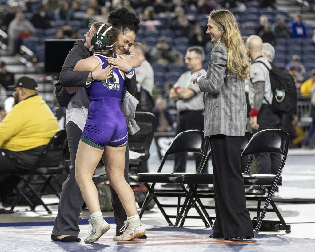 Edmonds-Woodways Hannah Baldock hugs her coaches after winning the 3A girls 140-pound championship title at the Mat Classic on Friday, Feb. 21, 2025 in Tacoma, Washington. (Olivia Vanni / The Herald)