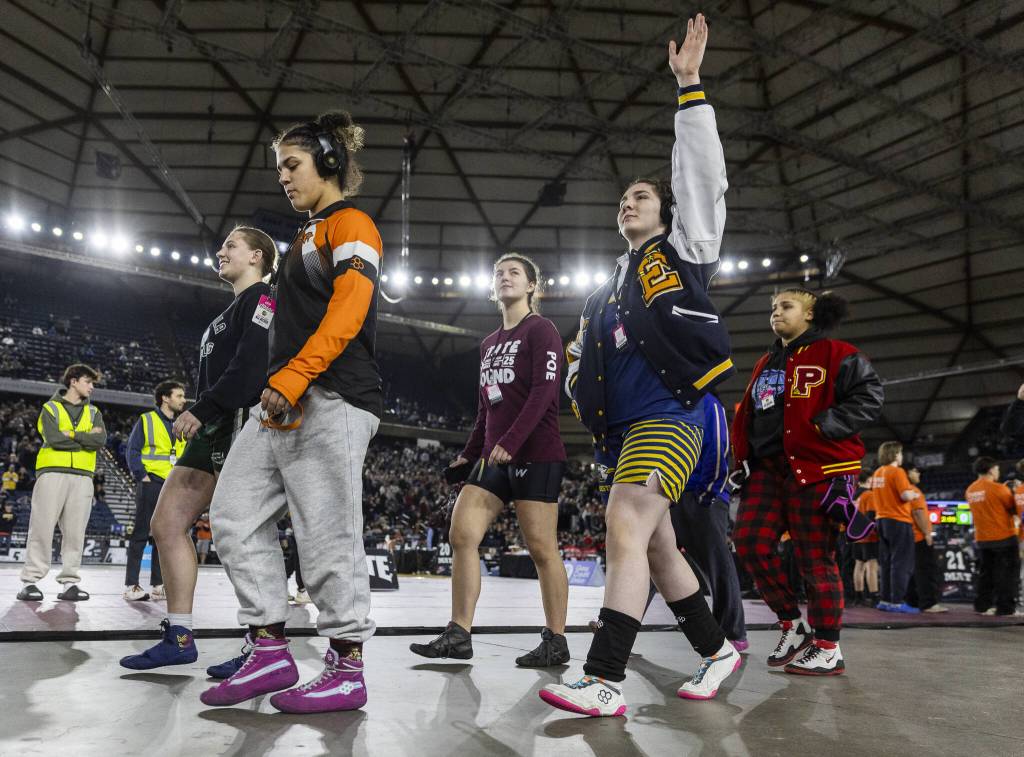 Everetts Mia Cienga waves as she walks onto the floor before her championship match at the Mat Classic on Friday, Feb. 21, 2025 in Tacoma, Washington. (Olivia Vanni / The Herald)
