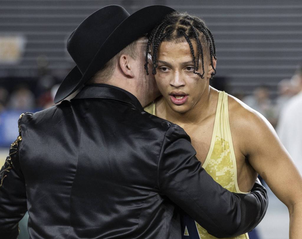 Arlingtons Tre Haines gets a hug from his coach after winning 4A boys 165-pound championship title at the Mat Classic on Friday, Feb. 21, 2025 in Tacoma, Washington. (Olivia Vanni / The Herald)