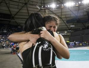 Jackson’s Emily Ortiz cries and hugs her coach, Chey Kawaihae, after winning the at the 4A girls 145-pound championship title Mat Classic on Friday, Feb. 21, 2025 in Tacoma, Washington. (Olivia Vanni / The Herald)
