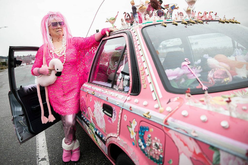 Marty Vale stands next to her hot pink and trinket covered Toyota Corolla on Thursday, Dec. 12, 2024 in Everett, Washington. (Olivia Vanni / The Herald)