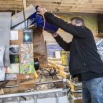 Robert Thompson pours a bucket of expired beer cans into his beer crusher. (Olivia Vanni / The Herald)