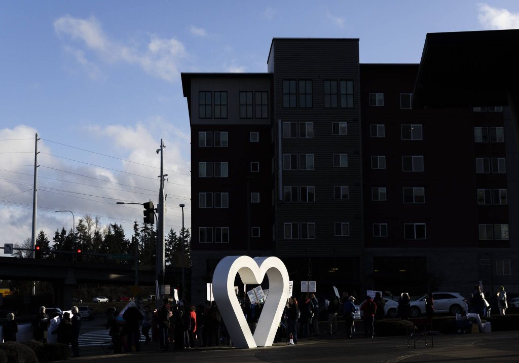 People gather for a Edmonds College faculty union rally as part of a national day of action outside of the Lynnwood Event Center on Tuesday, March 4, 2025 in Lynnwood, Washington. (Olivia Vanni / The Herald)