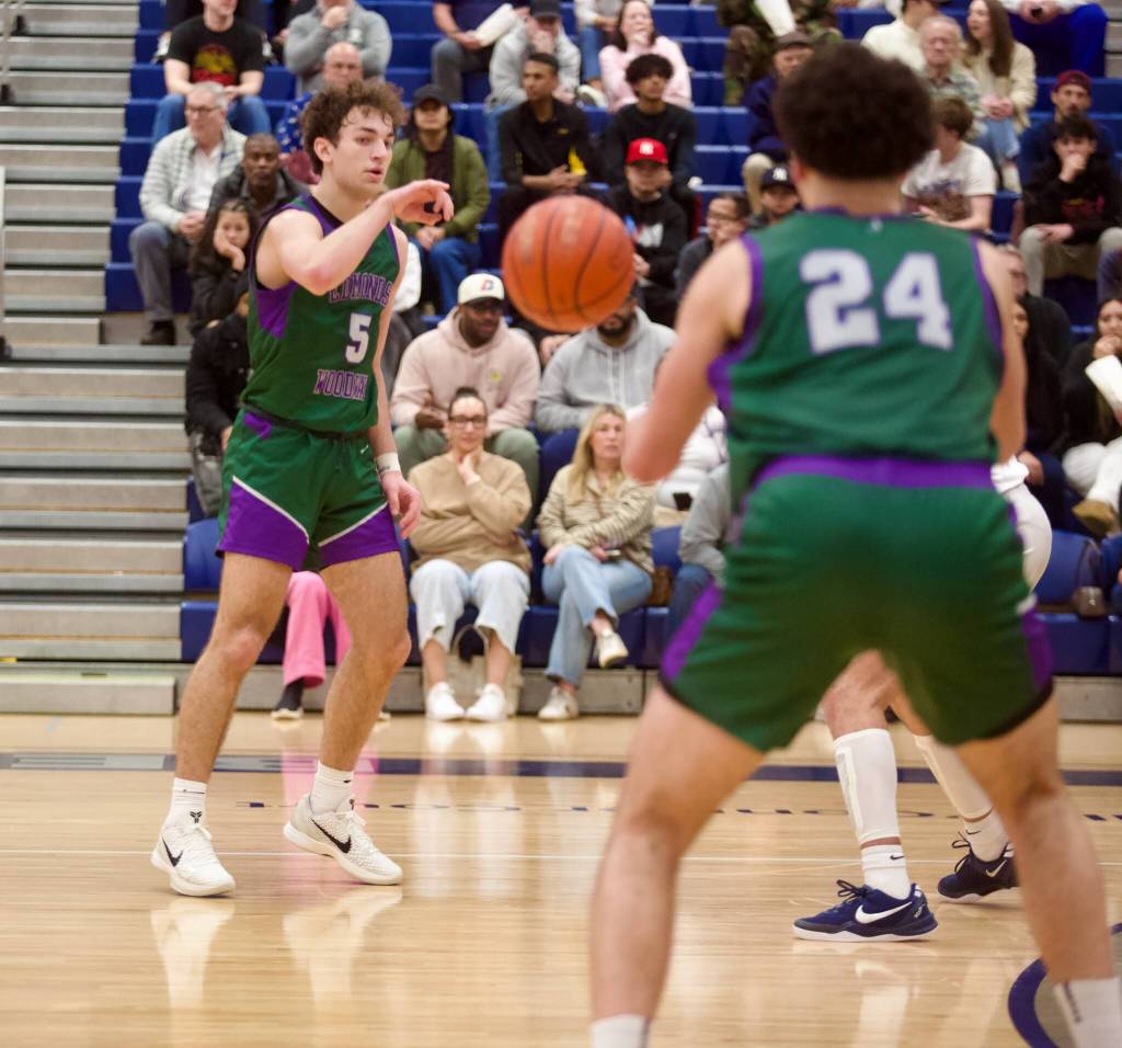 Edmonds-Woodway senior Cam Hiatt dishes a pass to junior Julian Gray (24) in the Warriors' 66-56 overtime win against Bellevue in the Boys 3A Basketball State tournament in Bellevue, Washington on March 1, 2025. (Joe Pohoryles / The Herald)