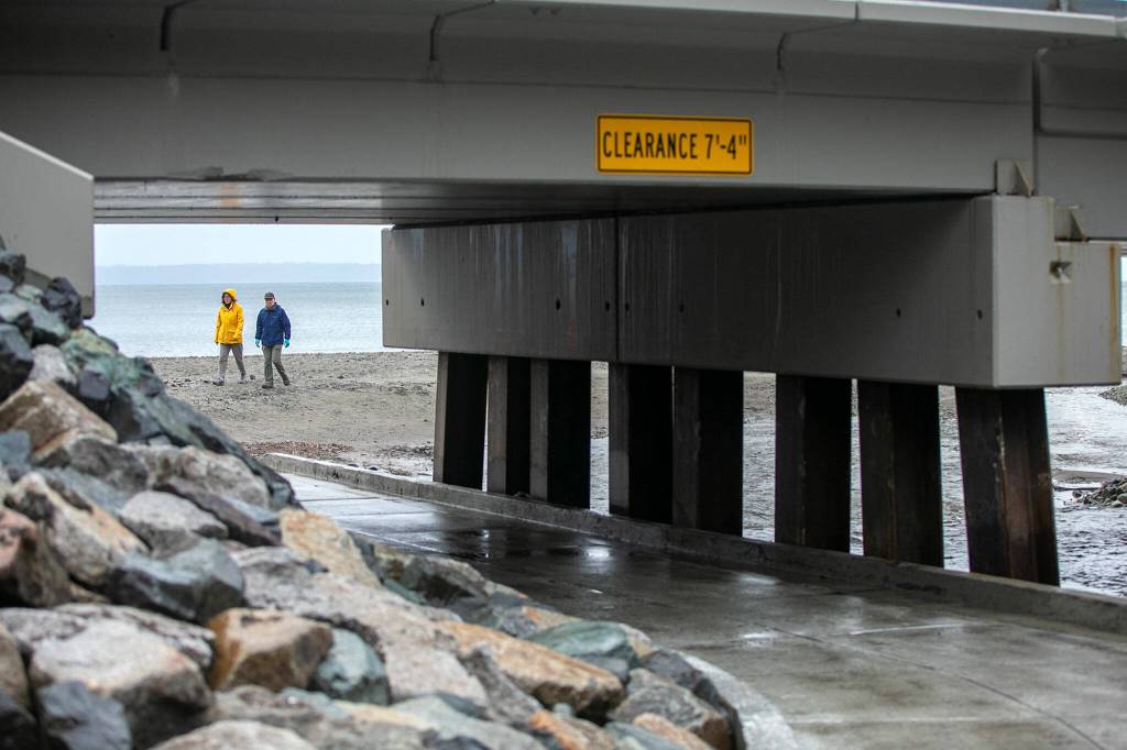 A couple begin the journey from the beach back to the parking lot after visiting Meadowdale Beach Park on Thursday, Jan. 12, 2023, in Edmonds, Washington. The walkway beneath the traintracks, seen in the foreground, has been completely redone and is now significantly more spacious than the previous path.(Ryan Berry / The Herald)